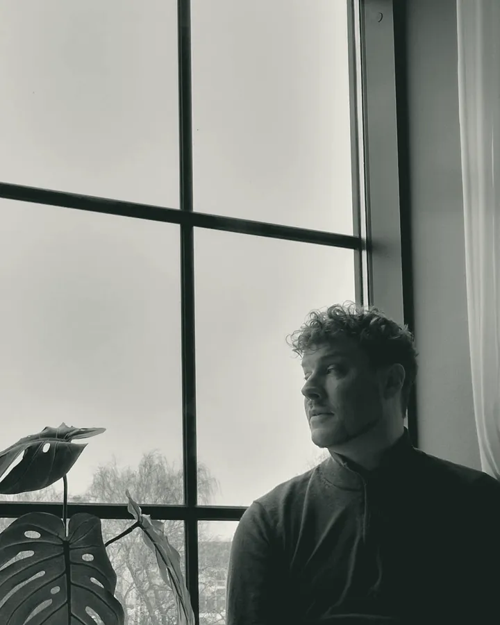 Oskar Uddenberg sitting by a tall window, looking out